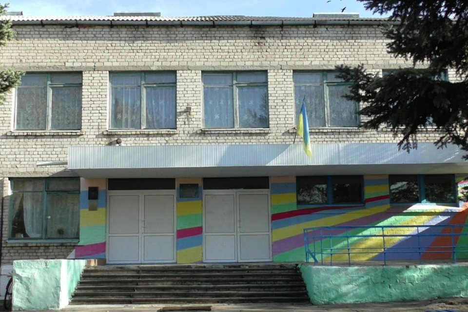 Головний корпус Андріївської гімназії: двоповерхова будівля з розмальованим у кольори веселки ґанком і державним прапором